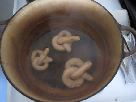 Add pretzels into boiling water and remove them with a slotted spoon.  Place on a cookie sheet, spray with water and add your toppings (some prefer to add them in the end).  Bake for the amount of time designated in your recipe.