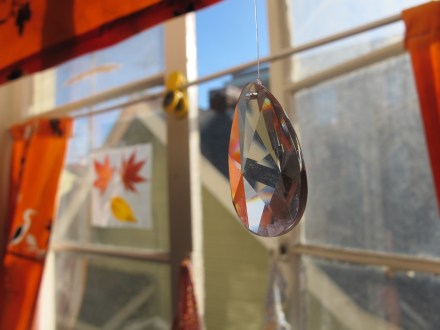 To further the magic that is our little urban kitchen, I have three prisms hanging from our sink window.  Our kitchen is the warmest place in the house and the most magical.  It's where we make crafts, we bake tasty food, and rainbows dance at certain times of the day!