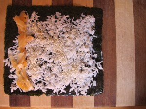 Layer of smoked salmon/lox.  I use one slice per roll.